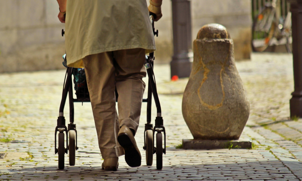 Ouder persoon loopt met rollator over straat