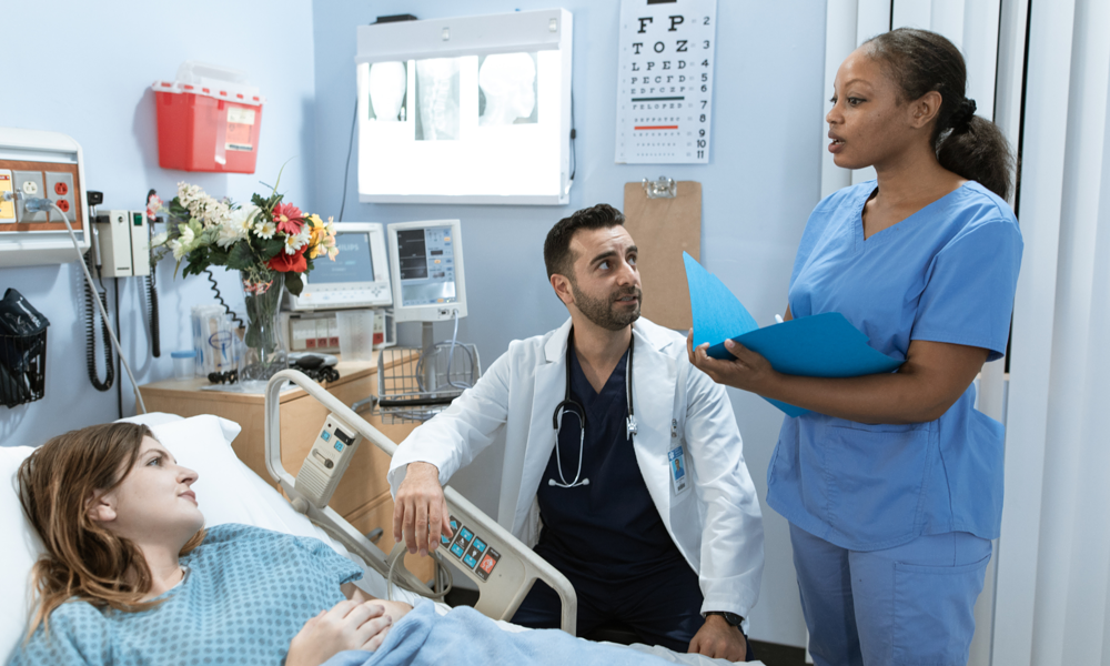 Een arts, verpleegkundige en patiënt in een ziekenhuisbed hebben een gesprek