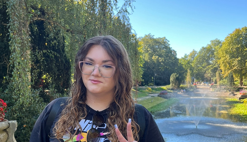 Woman posing with a peace sign in Noorderplantsoen park on a sunny day.