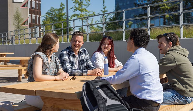 Five students talking at picknick table on Hanze campus