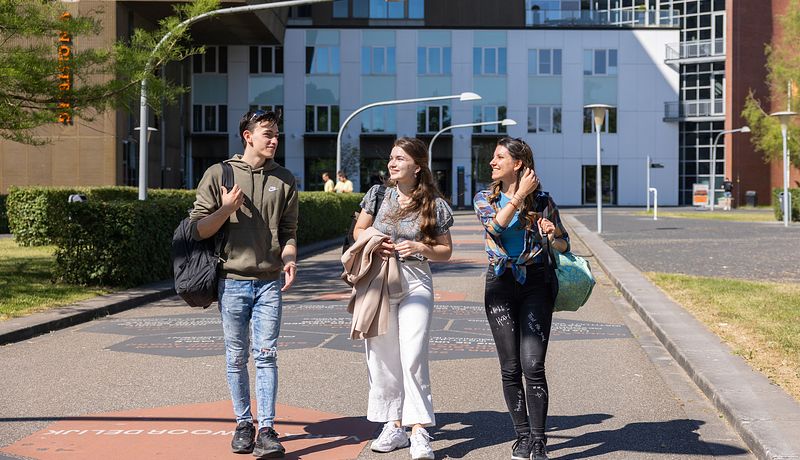 Three students walking along Walk of Fame in front of Van OlstBorg