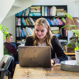 Student achter laptop met boekenkast 2022