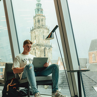 Student achter laptop in Forum met Martinitoren op de achtergrond