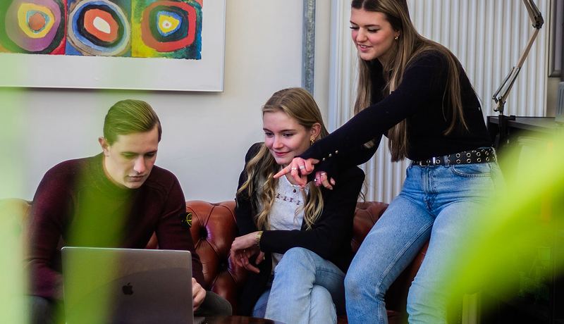Studierende schauen auf einen Laptop