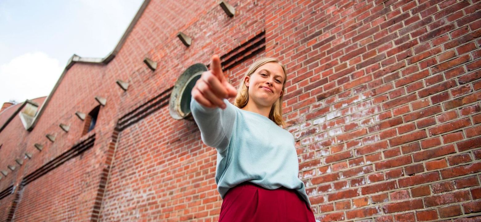 Woman walking in front of a brick building.