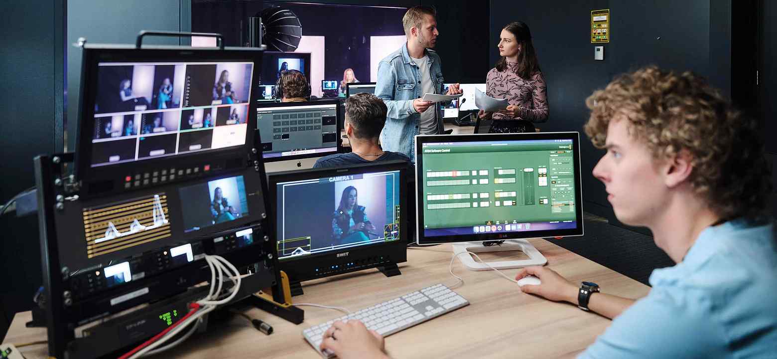 Een jonge man zit in een opname-studio achter verschillende beeldschermen studie Creative Business Saxion