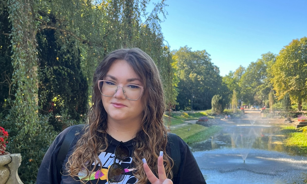 Woman posing with a peace sign in Noorderplantsoen park on a sunny day.
