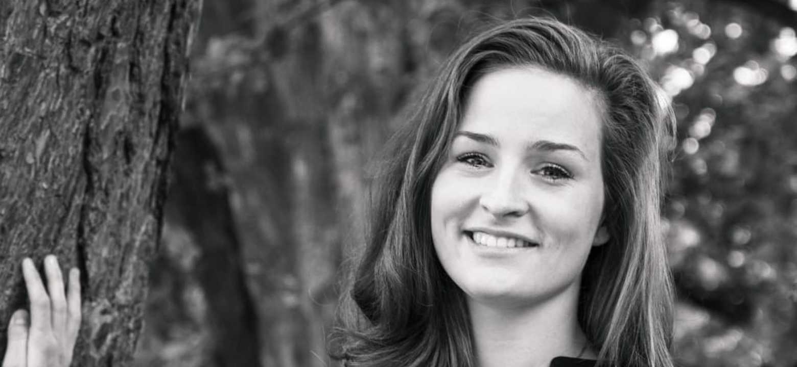 Zwart wit foto van vrouw die lacht en poseert bij een boom