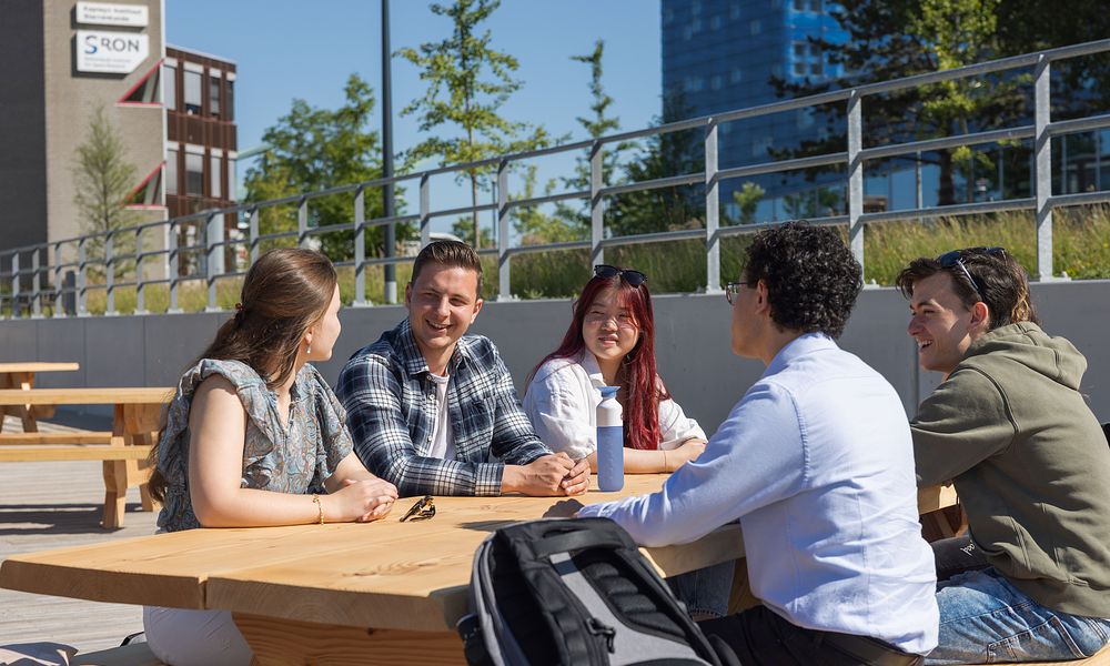 Group of students sitting at picknick table outside_HANZE230389.jpg