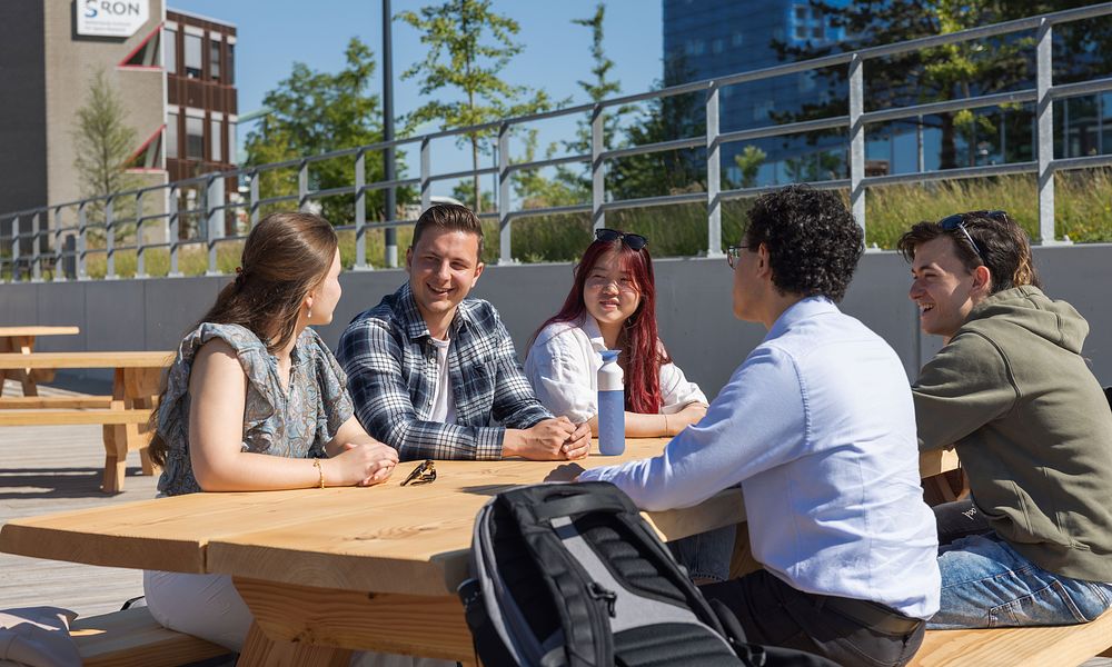 Five students talking at picknick table on Hanze campus