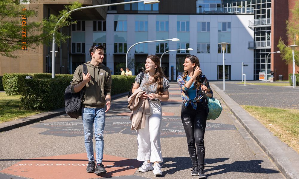 Three students walking along Walk of Fame in front of Van OlstBorg