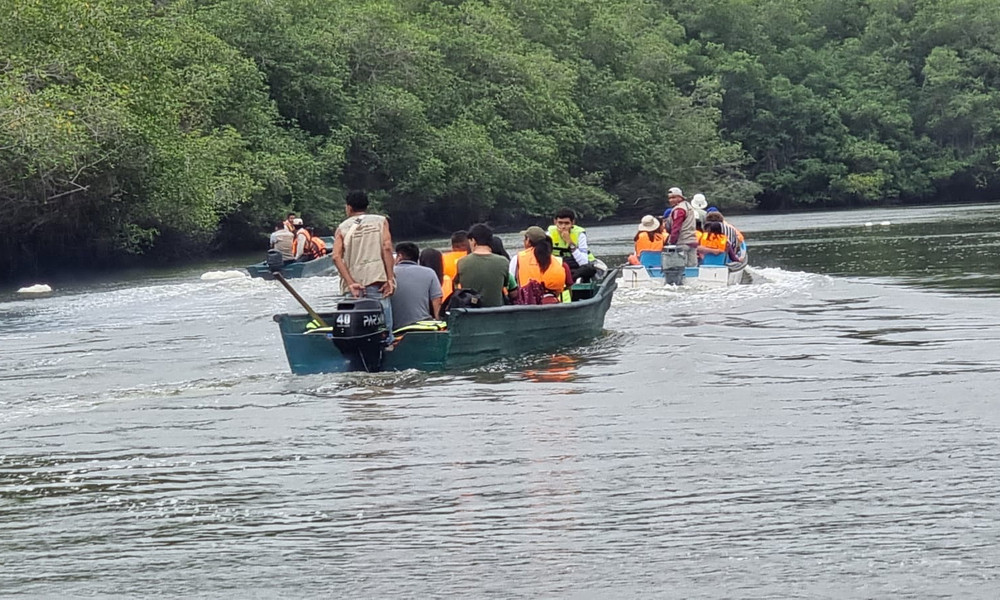Foto van mensen in oranje vasten die op twee bootjes door de rivier varen