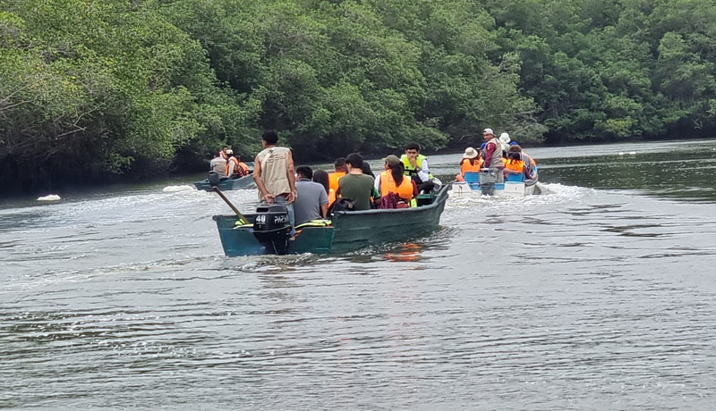 Foto van mensen in oranje vasten die op twee bootjes door de rivier varen
