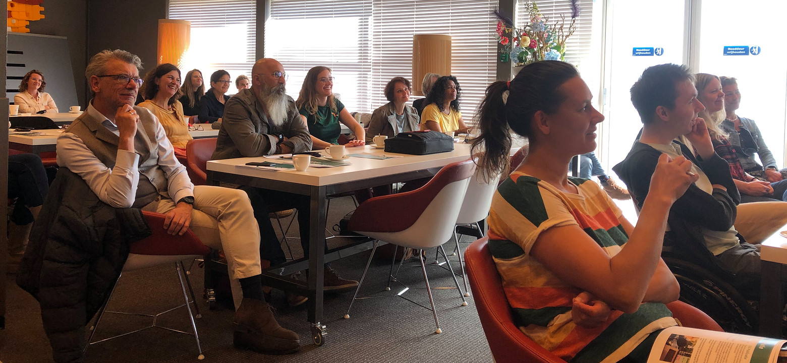 Zaal vol toehoorders tijdens podcastbijeenkomst