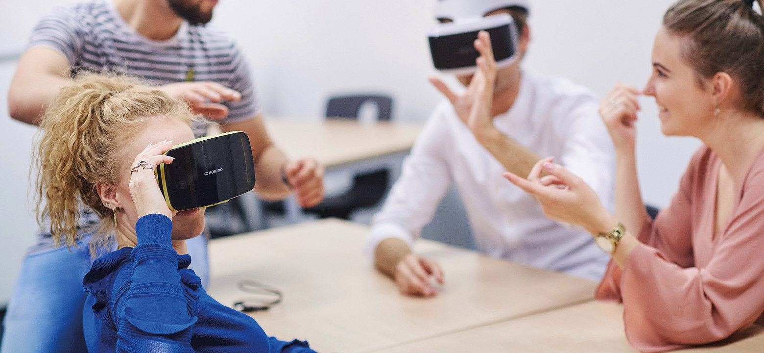 Jonge mensen zitten aan tafel en experimenteren met VR-brillen