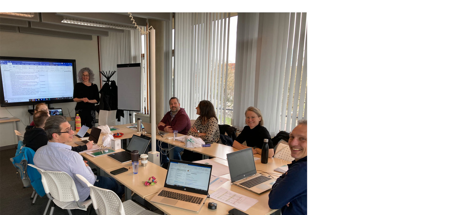 Het team zit achter laptops en volgt een presentatie