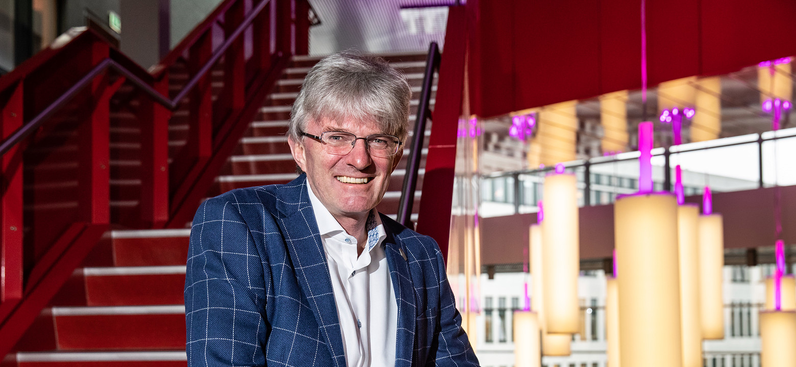 Man staat op trap en kijkt lachend in de camera