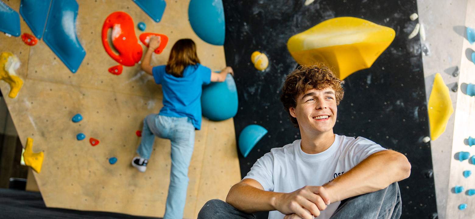 Jongen zit op de grond in een boulderhal.