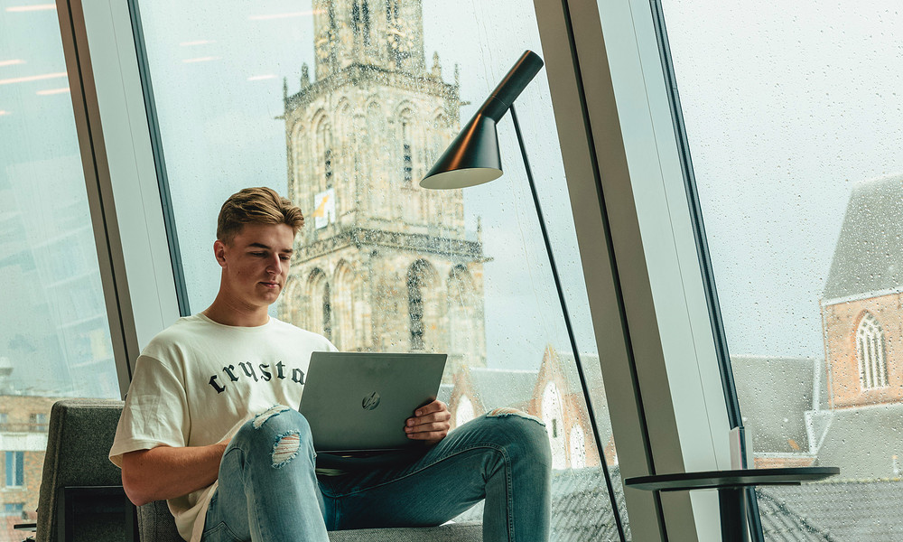 Student achter laptop in Forum met Martinitoren op de achtergrond