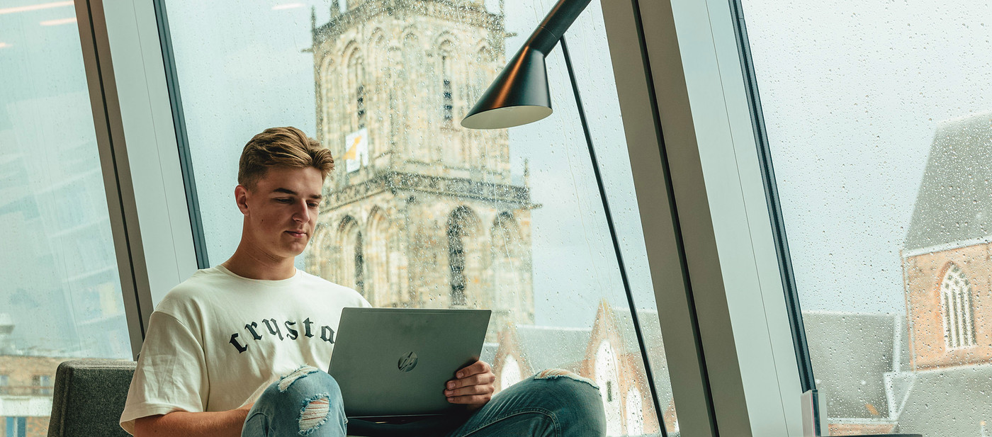 Student achter laptop in Forum met Martinitoren op de achtergrond