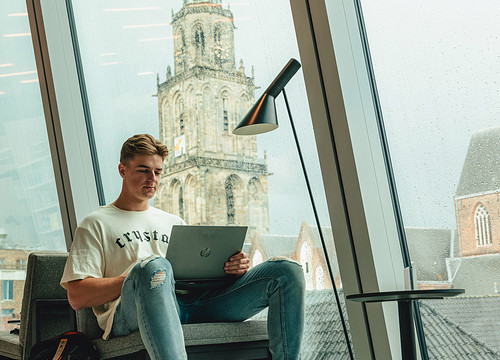 Student achter laptop in Forum met Martinitoren op de achtergrond