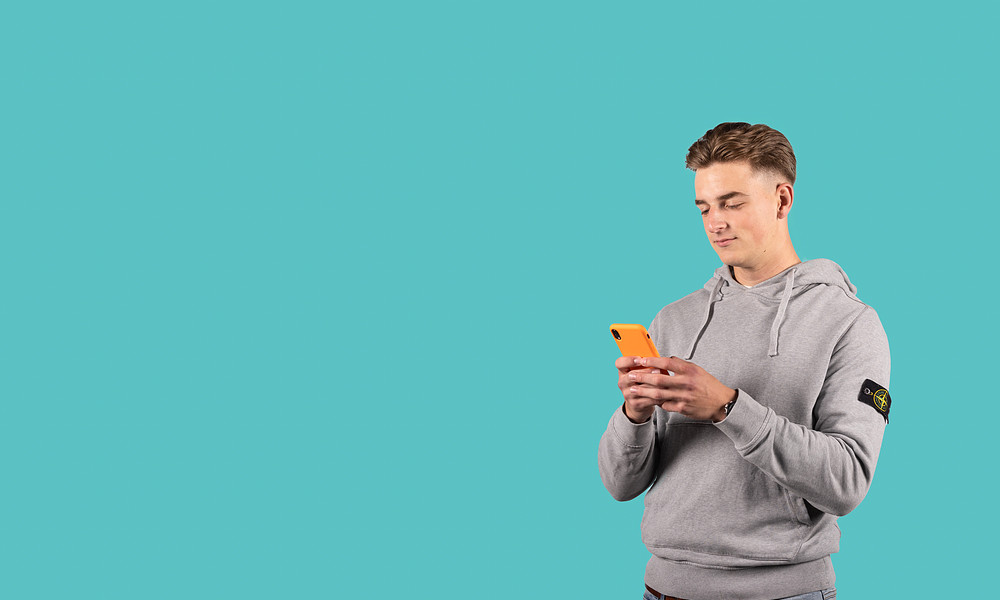 Student met oranje smartphone en grijze trui