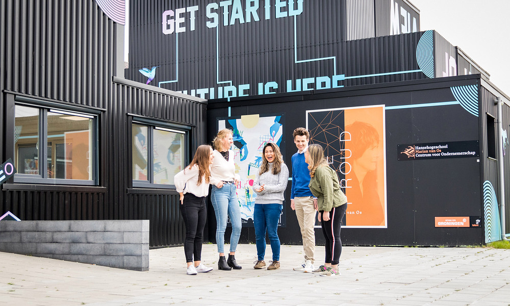 Five students standing outside in fron of container buildings with text 'get started'